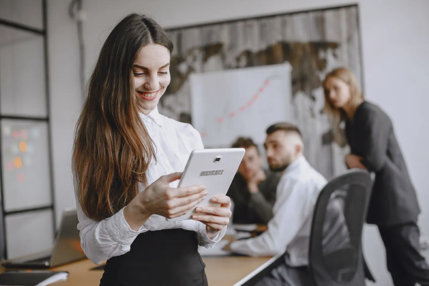 Profissional sorrindo com um tablet durante reunião de equipe